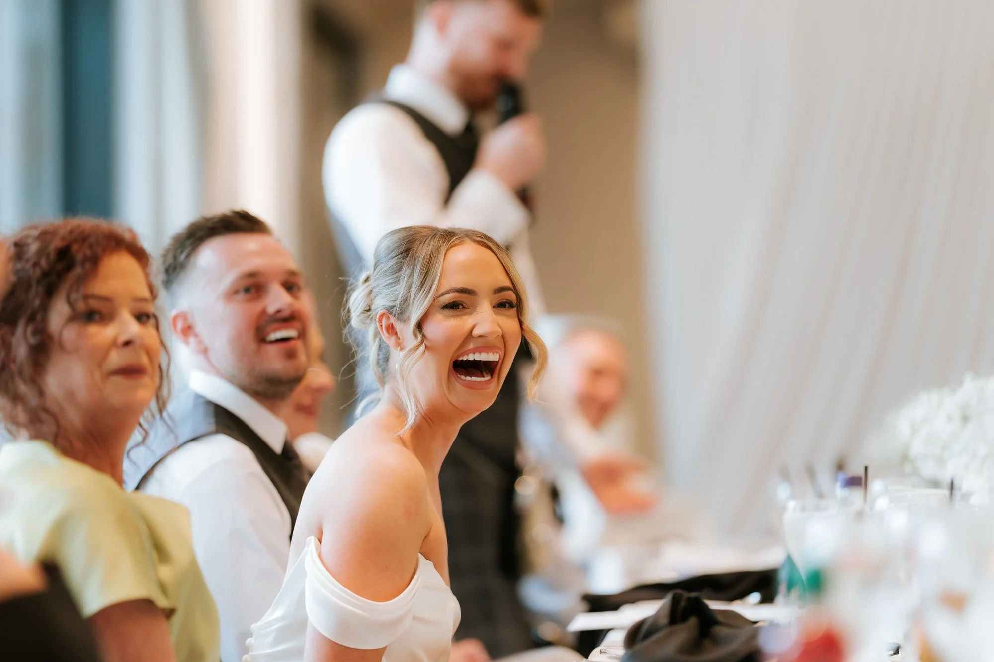 Elle laughing during the speeches with Adam seated beside her