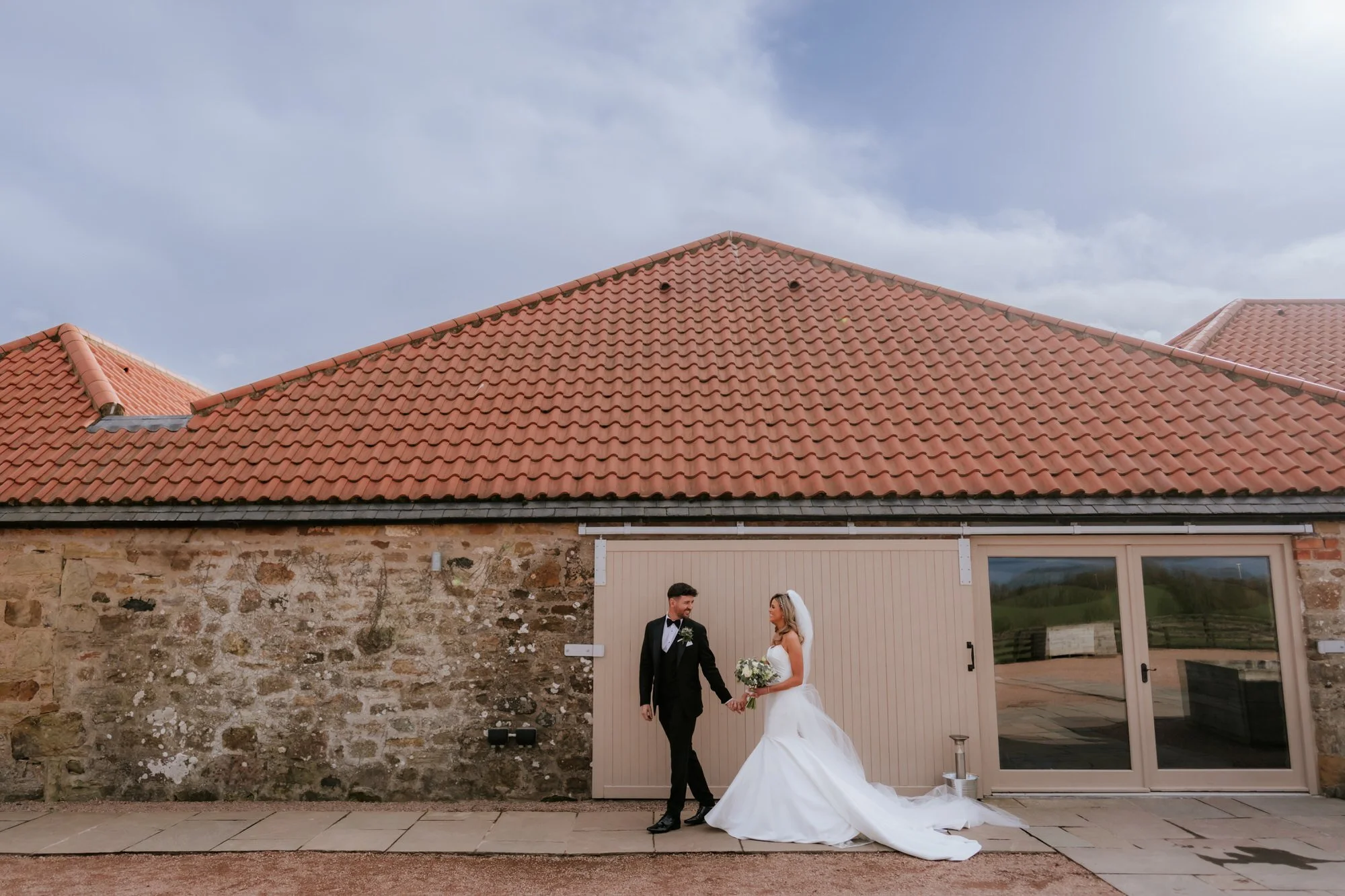 Natalie and Jamie together beside a stone wall at Falside Mill