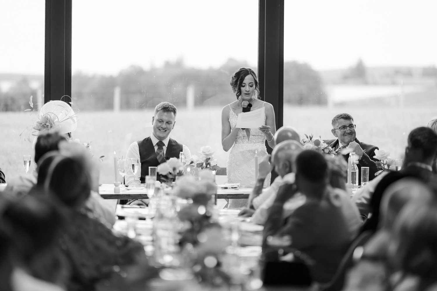 Lauren giving her wedding speech while guests listen, photographed in black and white.
