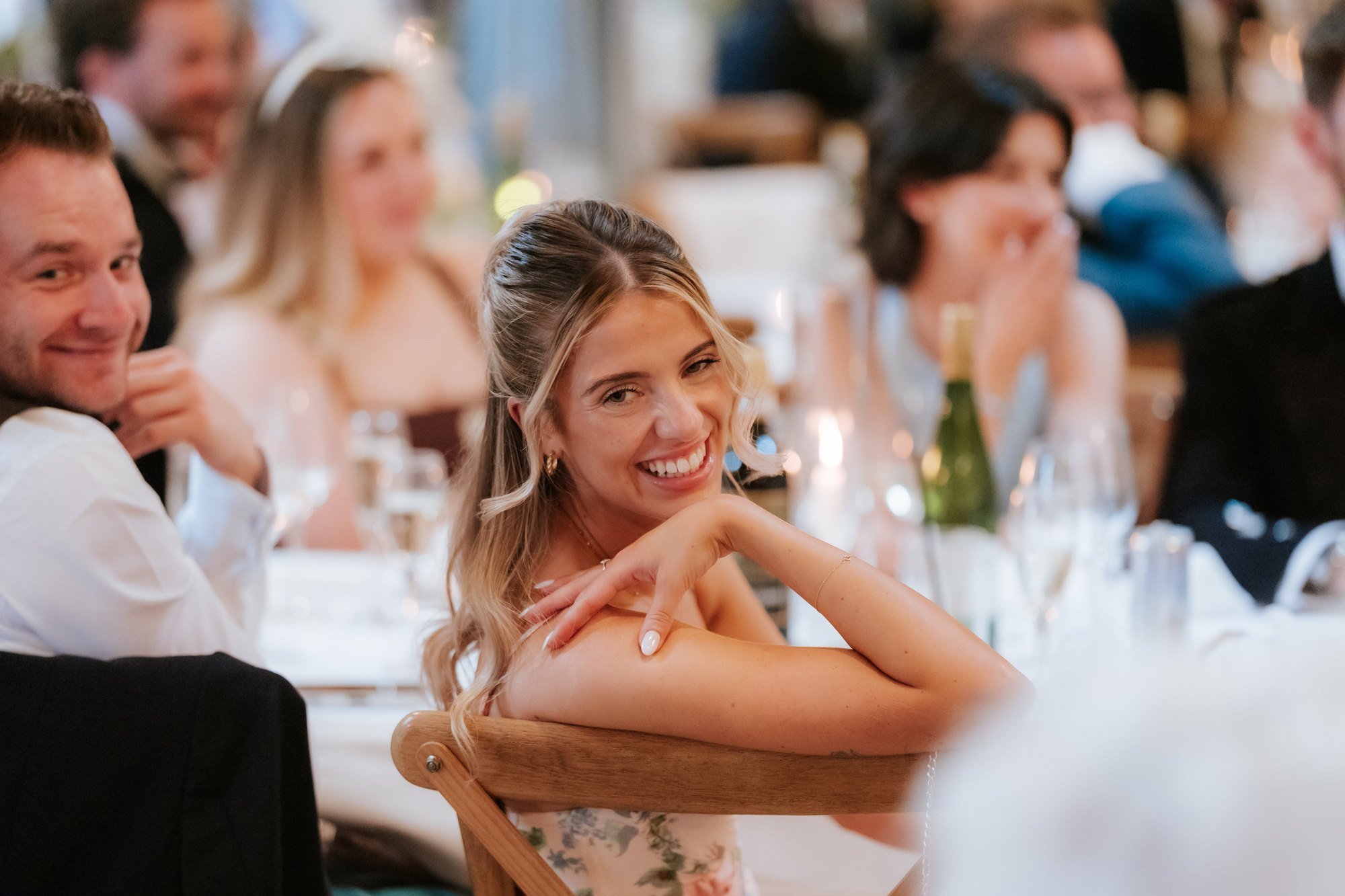 Wedding guests smiling and laughing during the speeches.