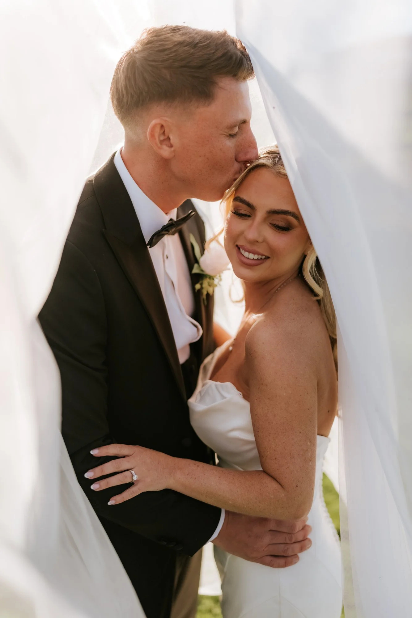Aiden kissing Taylor on the forehead beneath her veil.