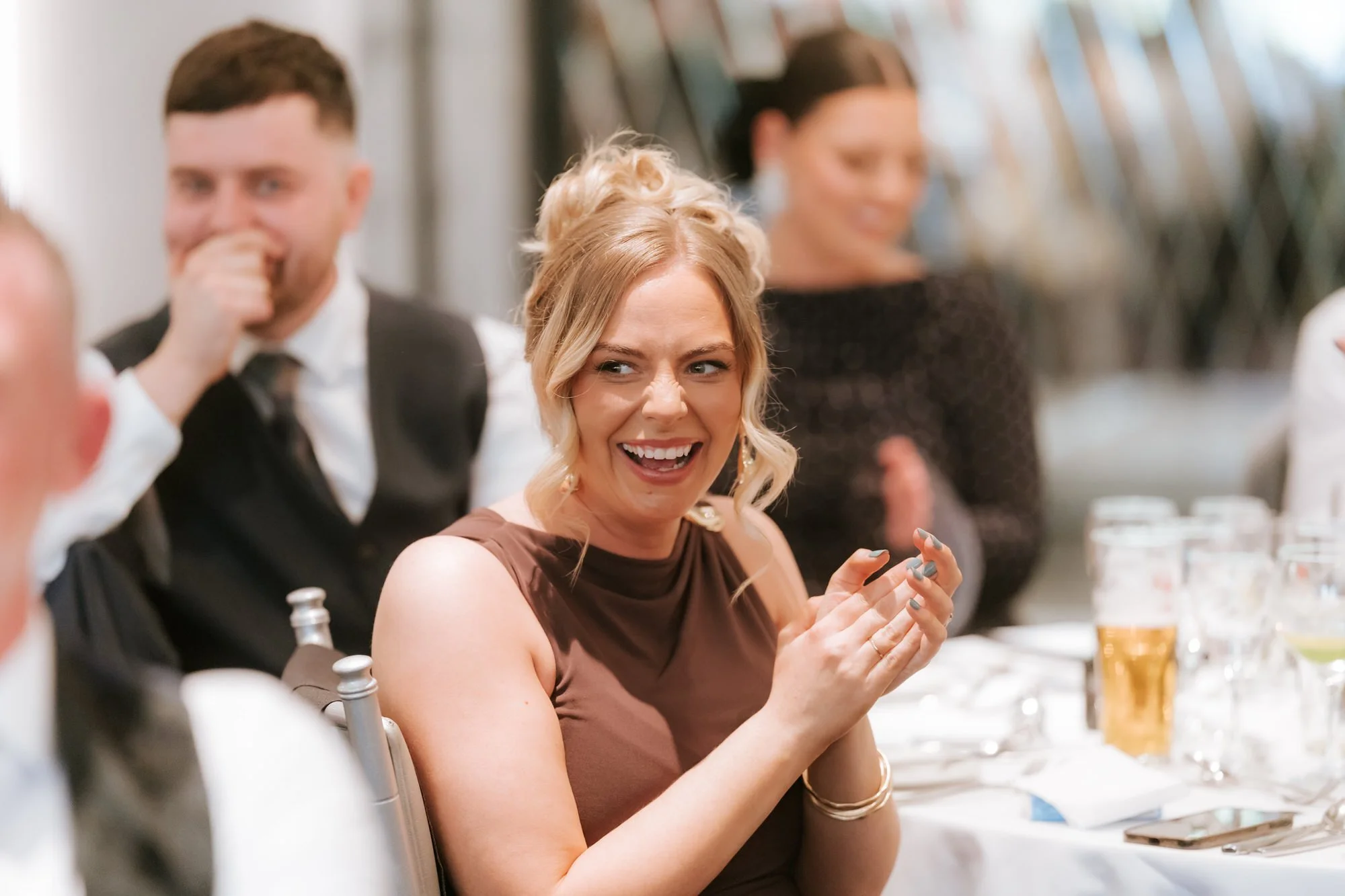 A guest in a brown dress laughing and applauding