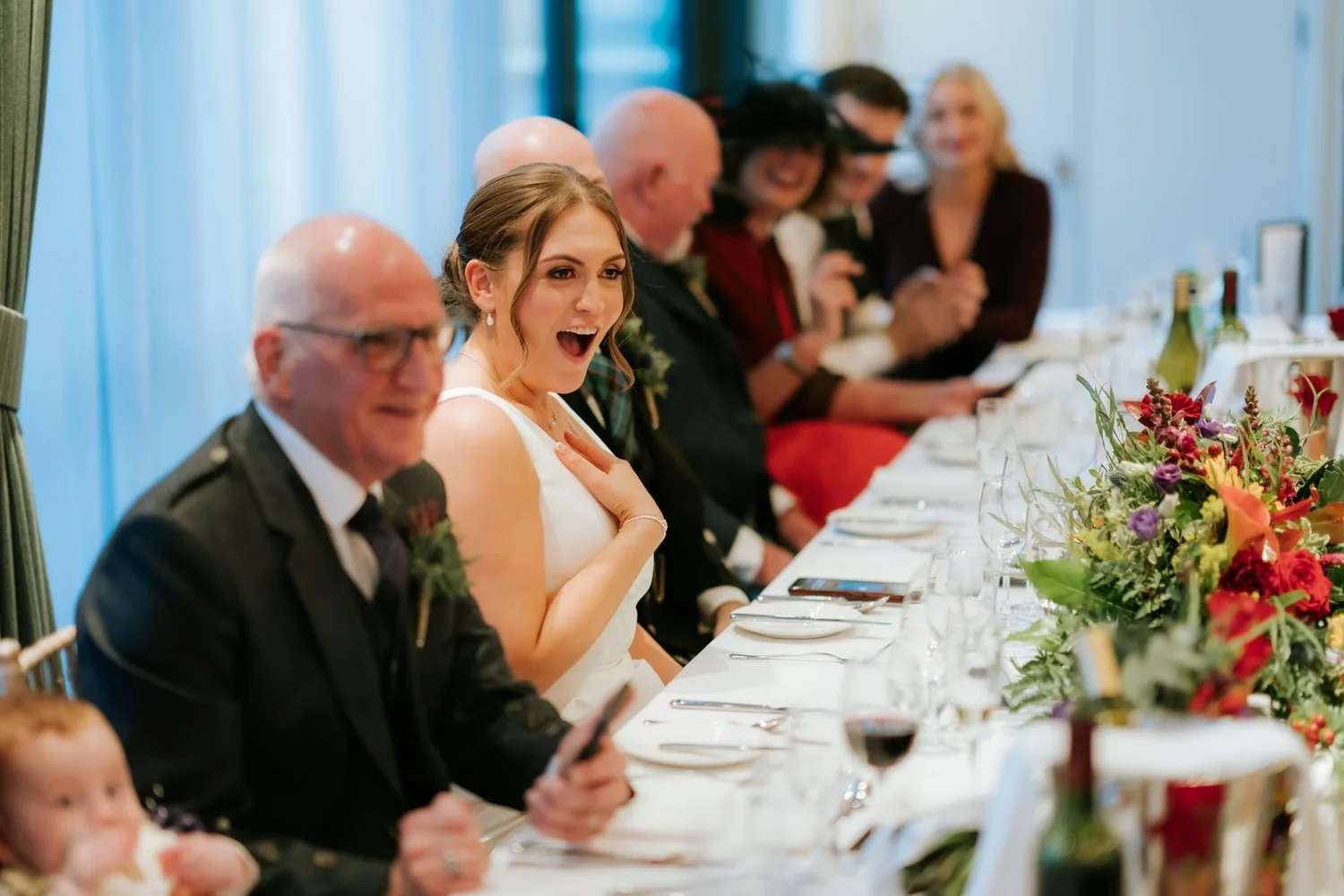 Kendall reacting to a story during the speeches with Ewen smiling beside her.