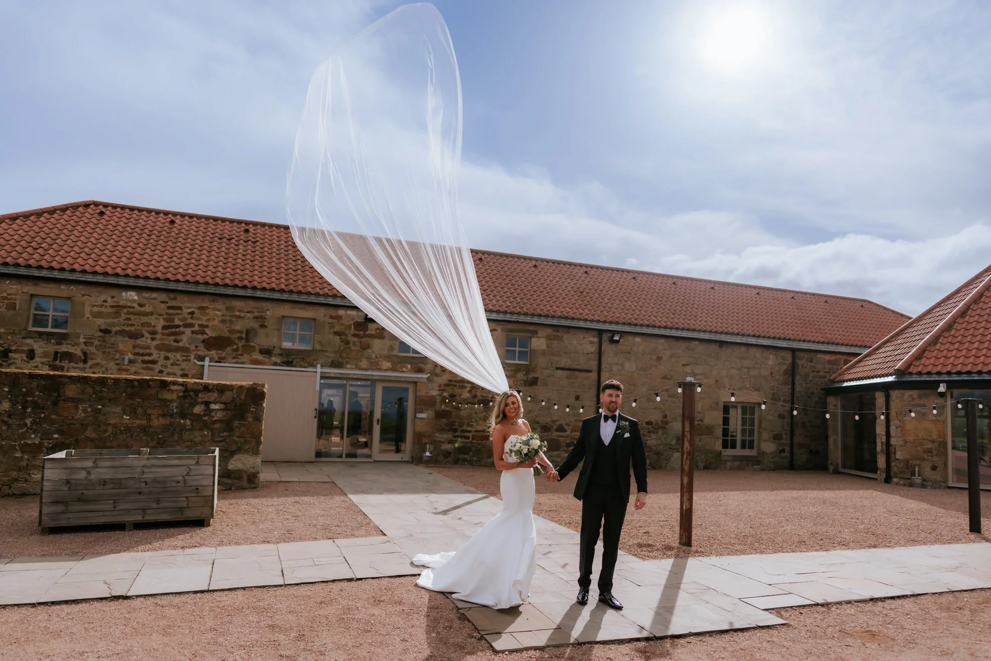 Natalie and Jamie laughing as her veil blows around them