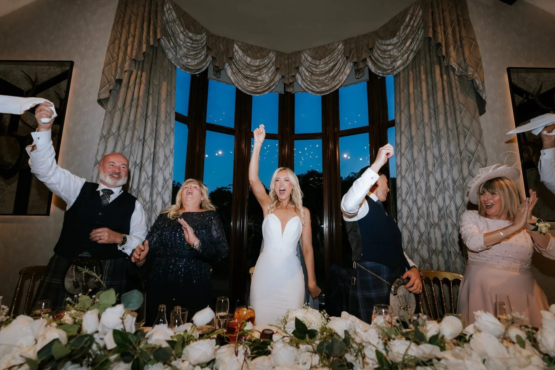 Lauren and guests celebrating with their hands in the air at the top table.
