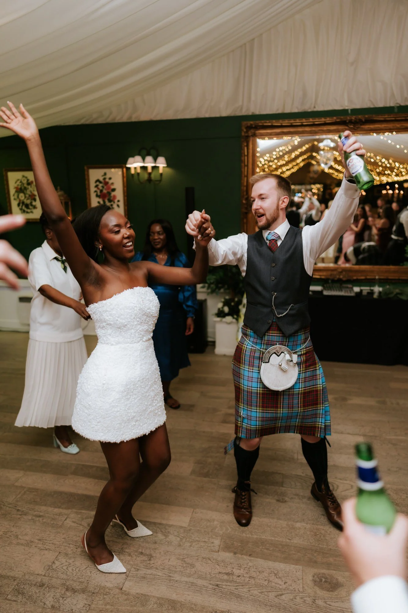 Kuda in her short evening dress dancing with Jamie, both with their arms raised.