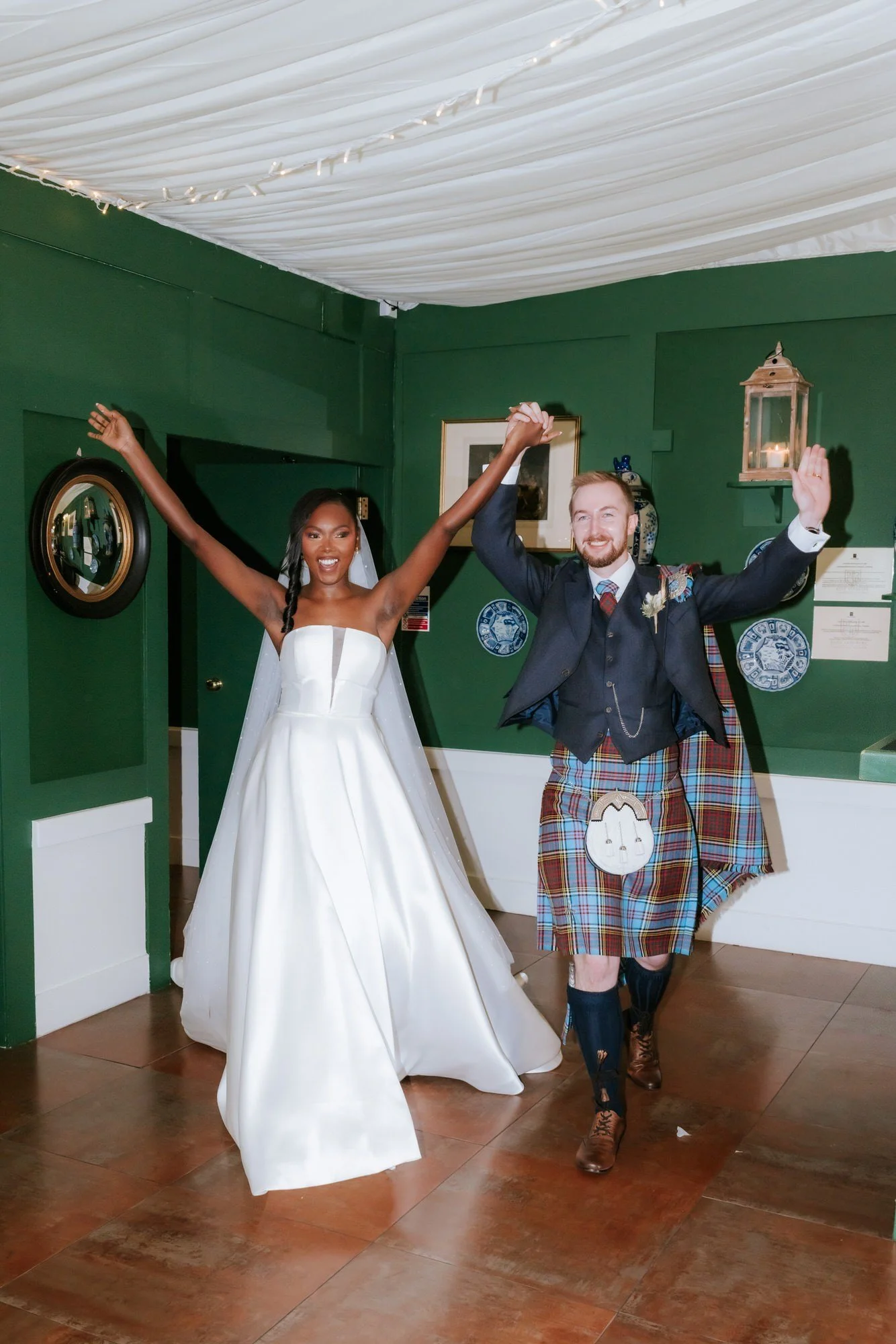 Kuda and Jamie raising their arms as they enter the wedding reception.