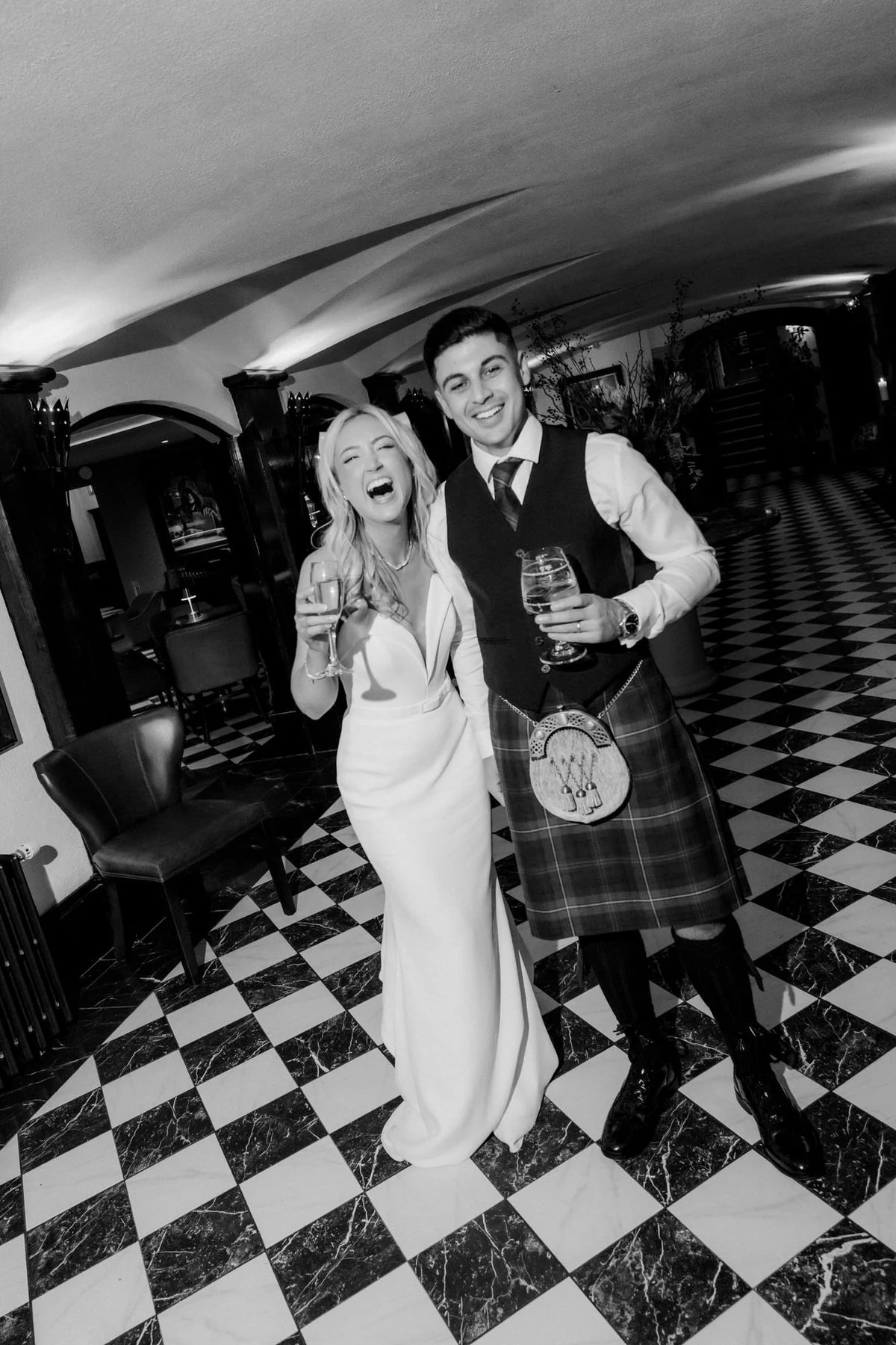 Lauren and Zen laughing together on the chequered floor, photographed in black and white.