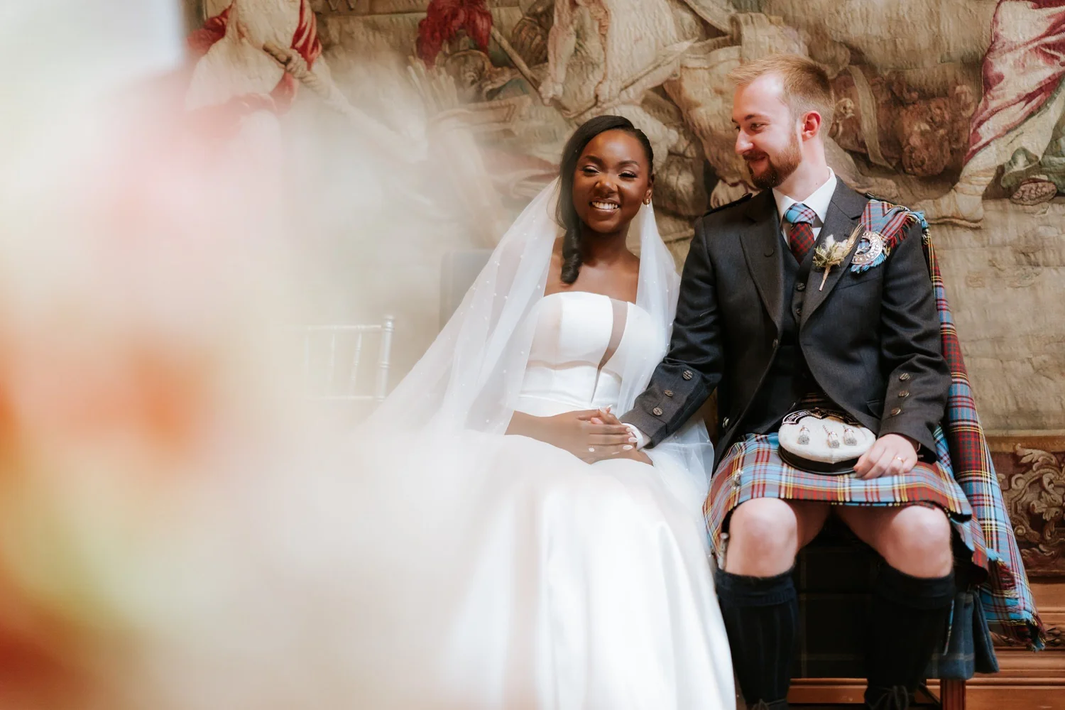 The newlyweds holding hands, photographed through the foreground.