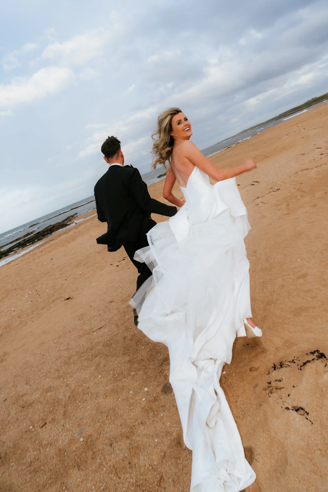 Natalie looking back and laughing as she runs on Kingsbarns beach