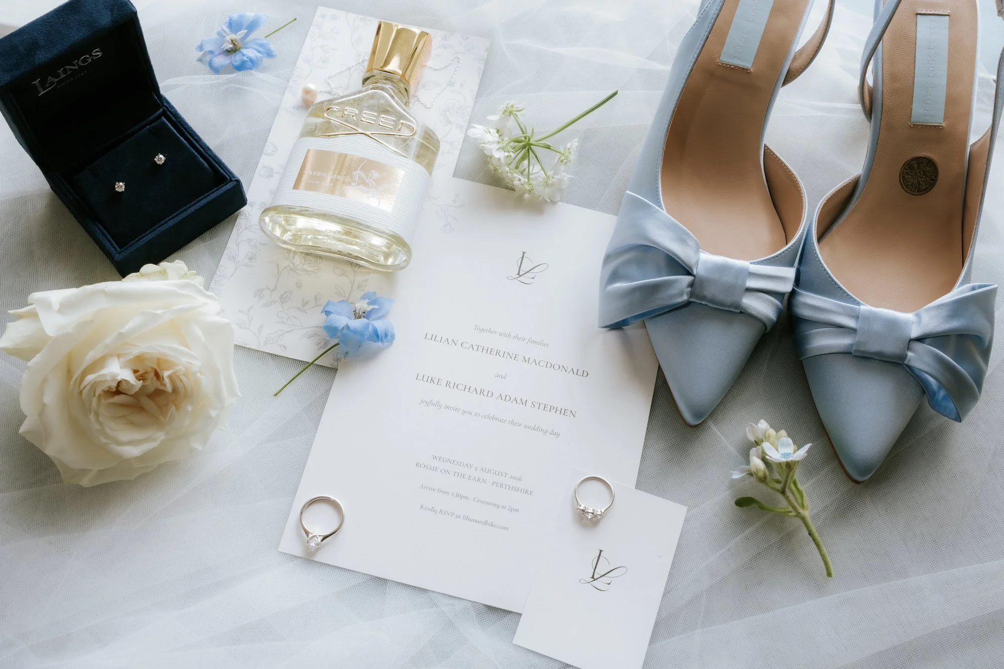 Lilian’s blue bridal shoes, perfume and wedding stationery laid out on the wedding morning.