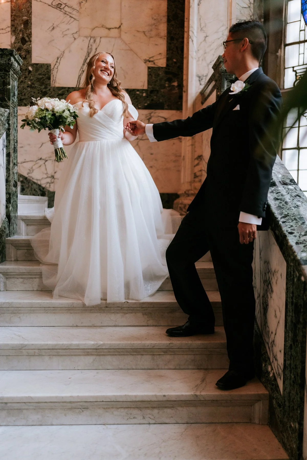 Carl taking Allie’s hand as she walks down the marble staircase at The Scotsman Hotel.