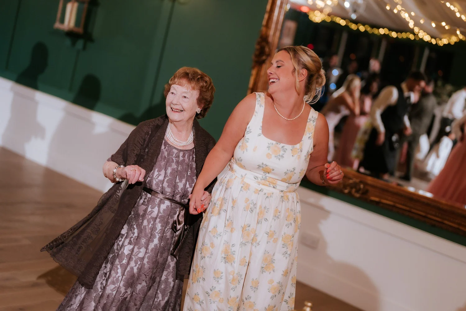 Two wedding guests holding hands and dancing together.