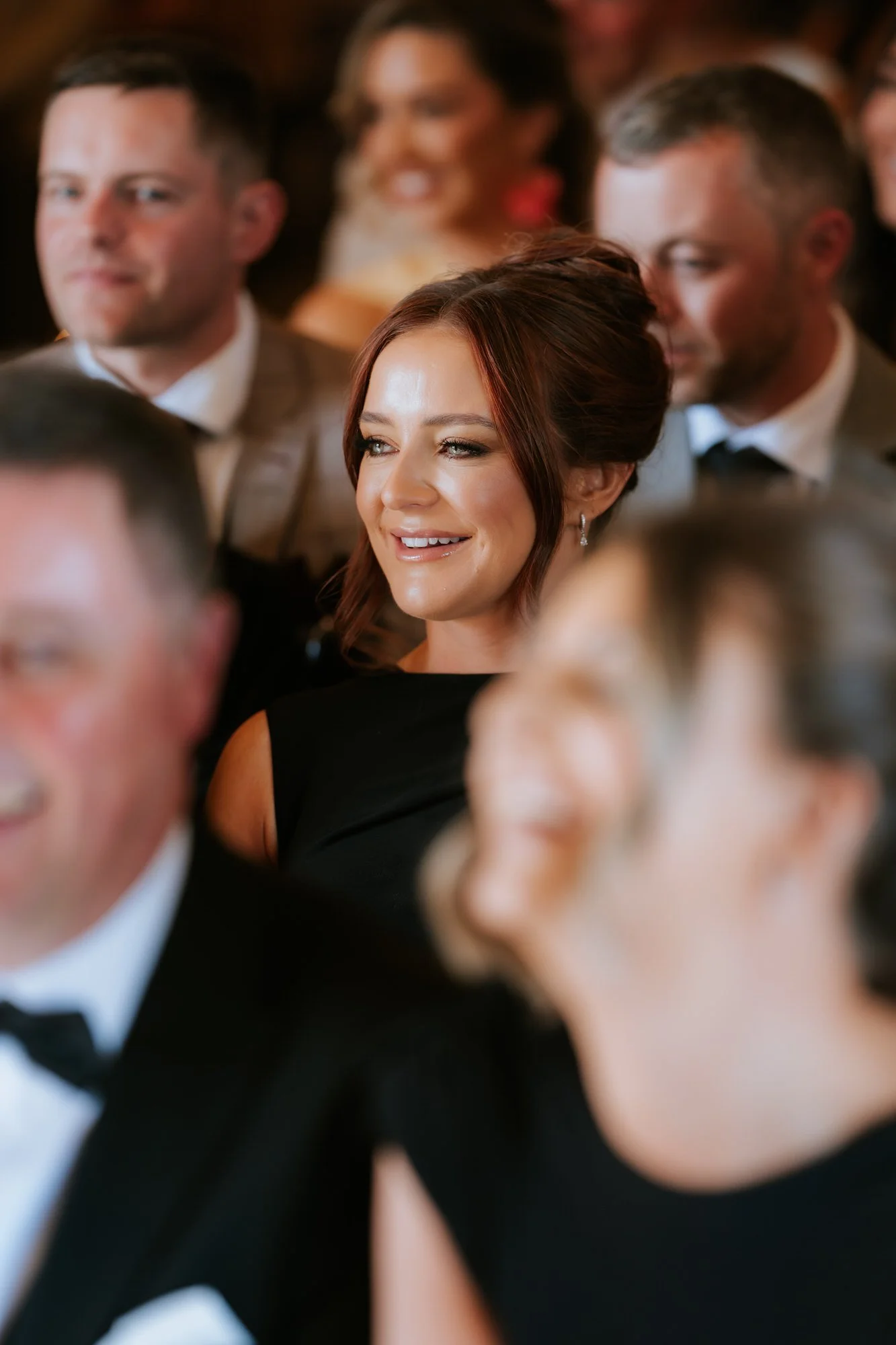 An auburn-haired bridesmaid smiling during the ceremony