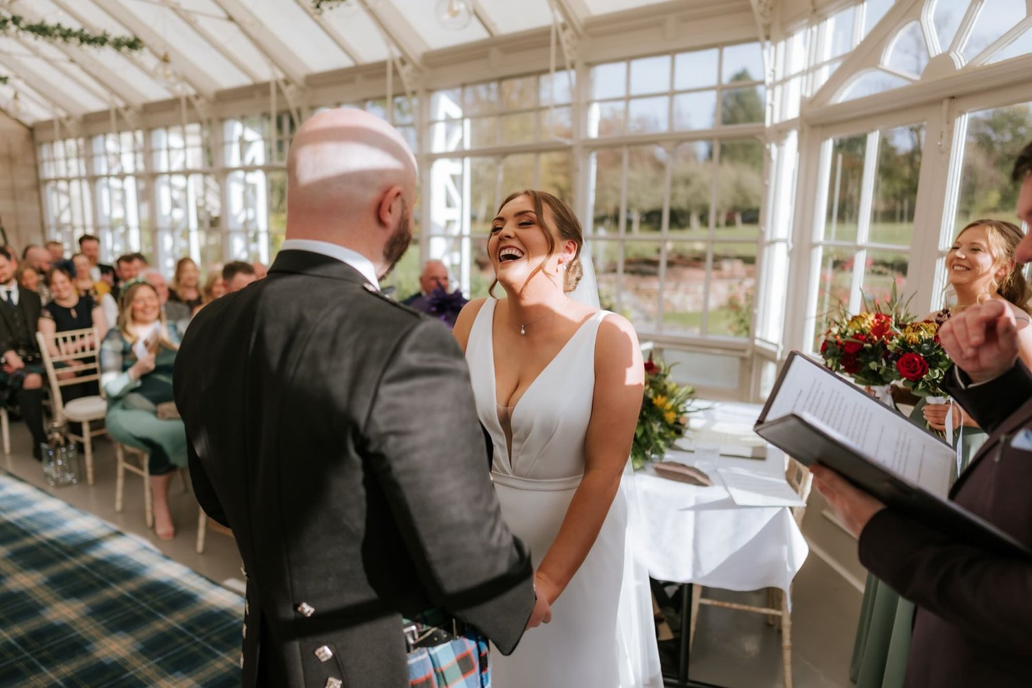 Kendall laughing with Ewen during their wedding ceremony at SCHLOSS Roxburghe.