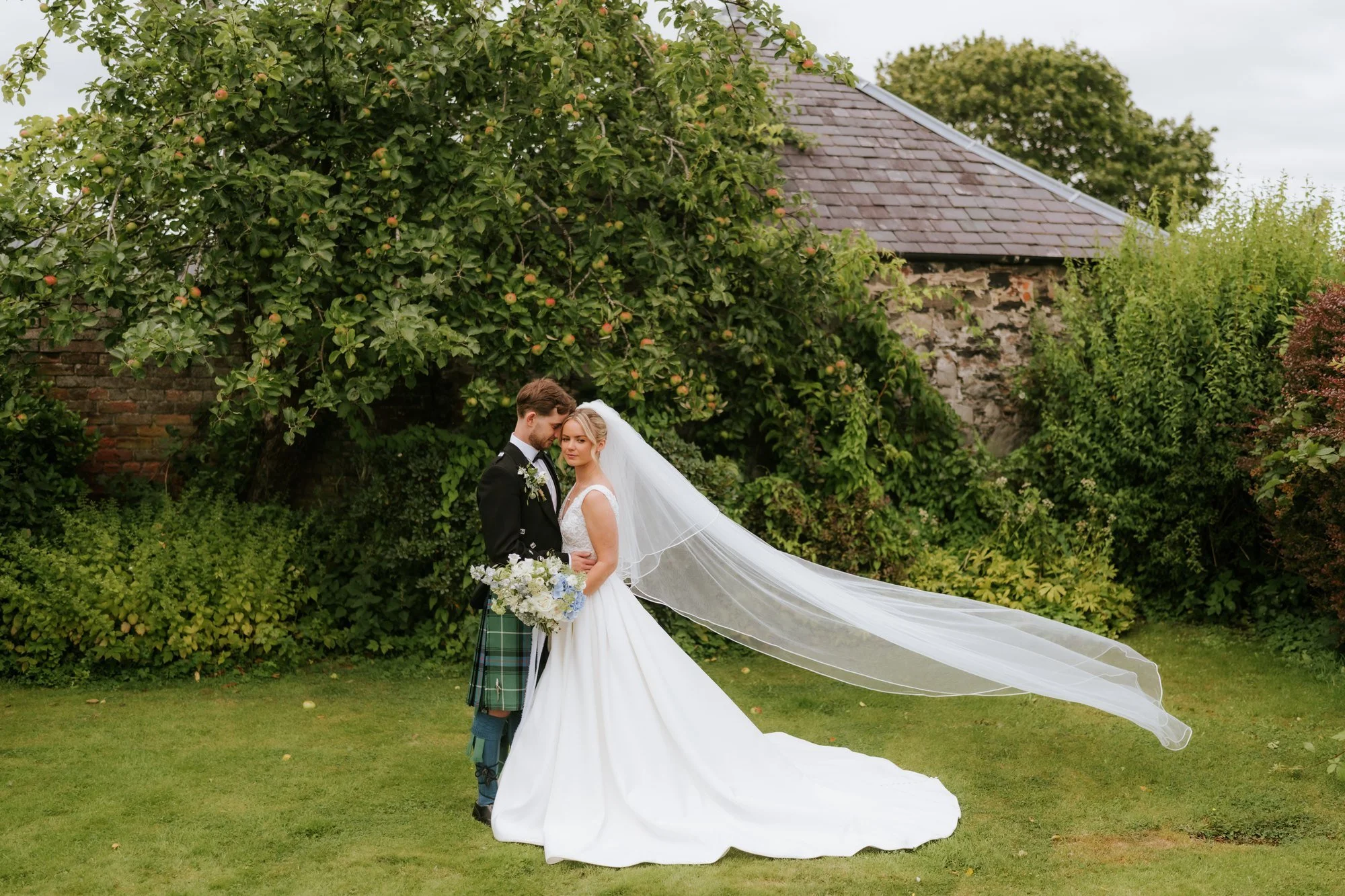 Lilian’s veil catching the breeze as she and Luke embrace in the garden.