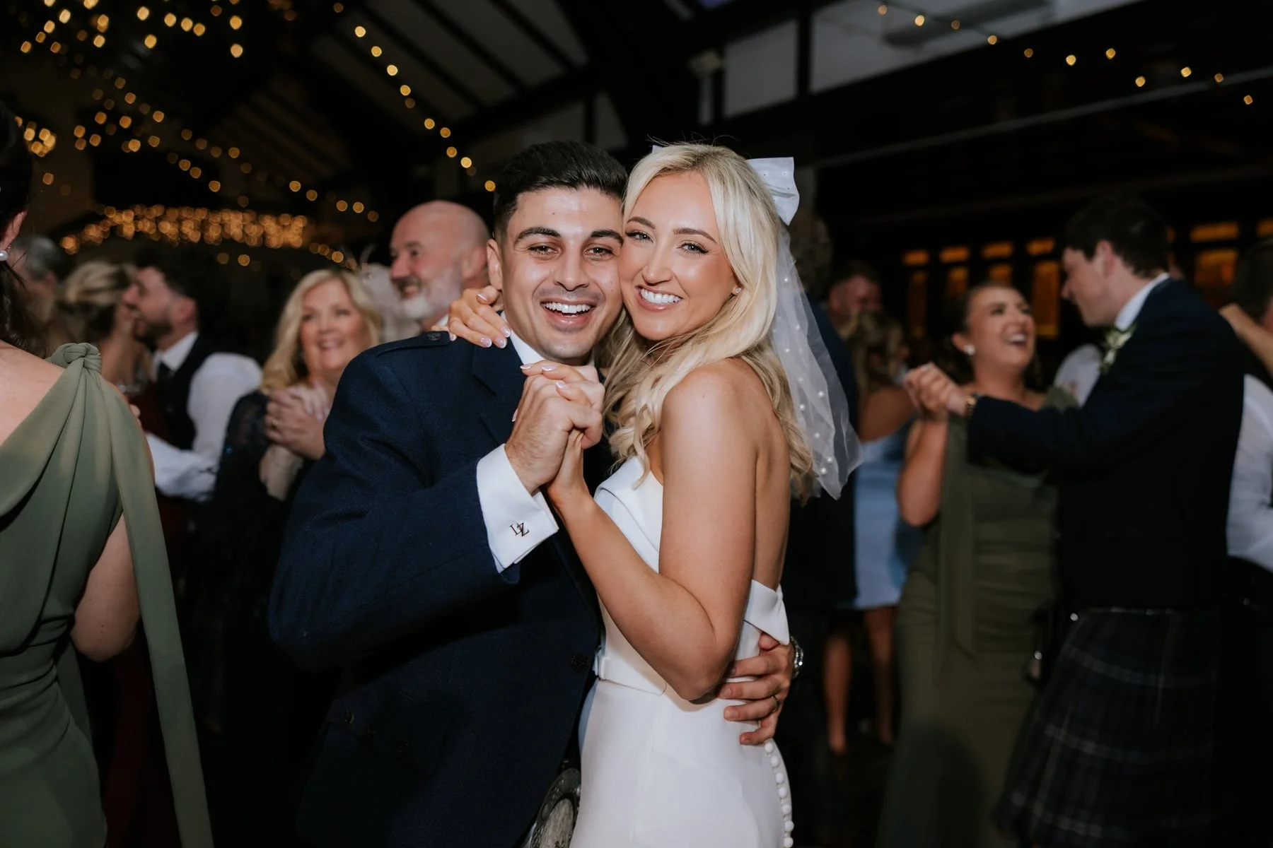 Lauren and Zen smiling together on the dance floor with their guests around them.
