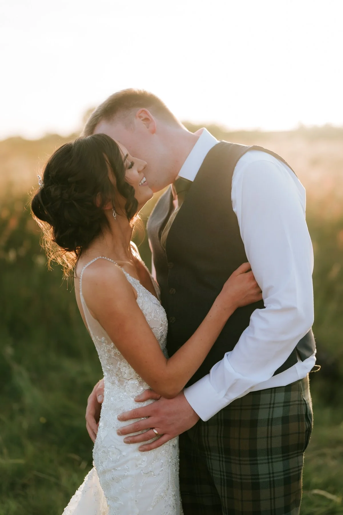 Lauren and Jamie smiling close together with the evening sun behind them.