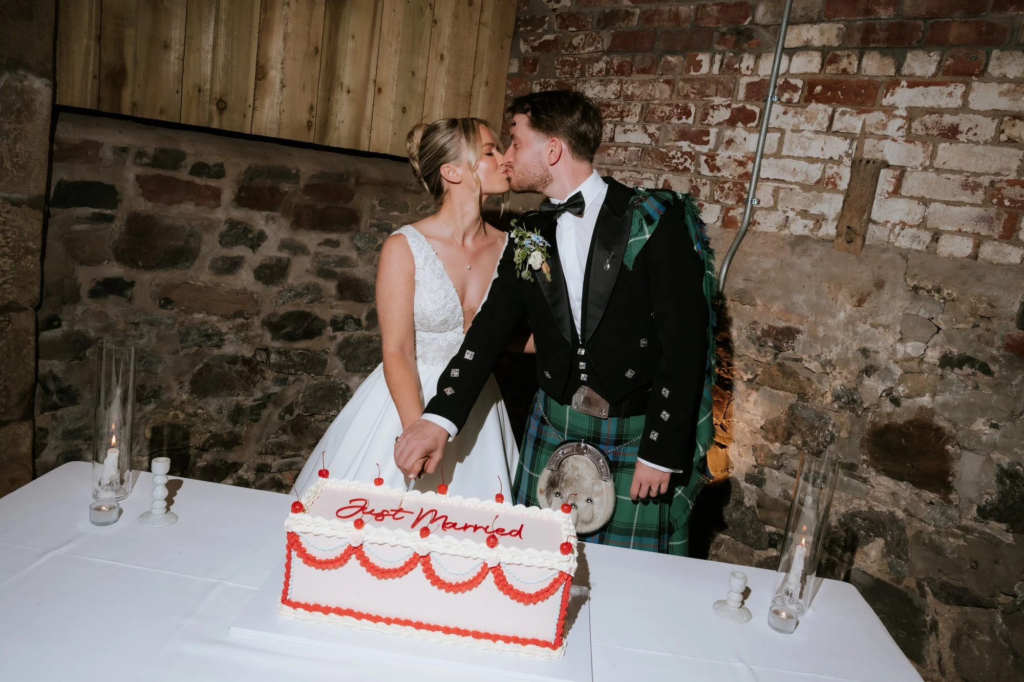 Lilian and Luke kissing as they cut their wedding cake.