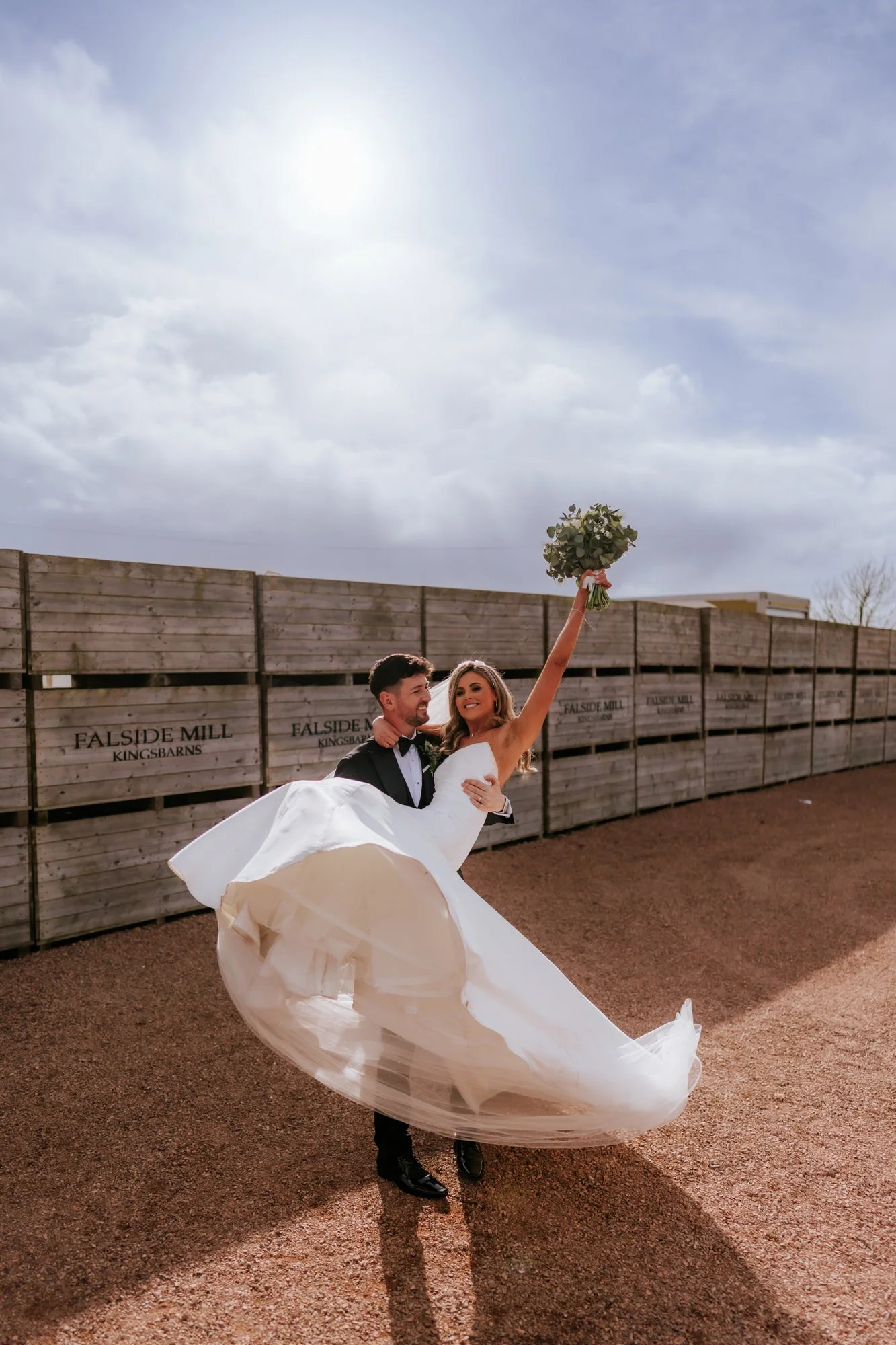 Jamie carrying Natalie as she raises her bouquet