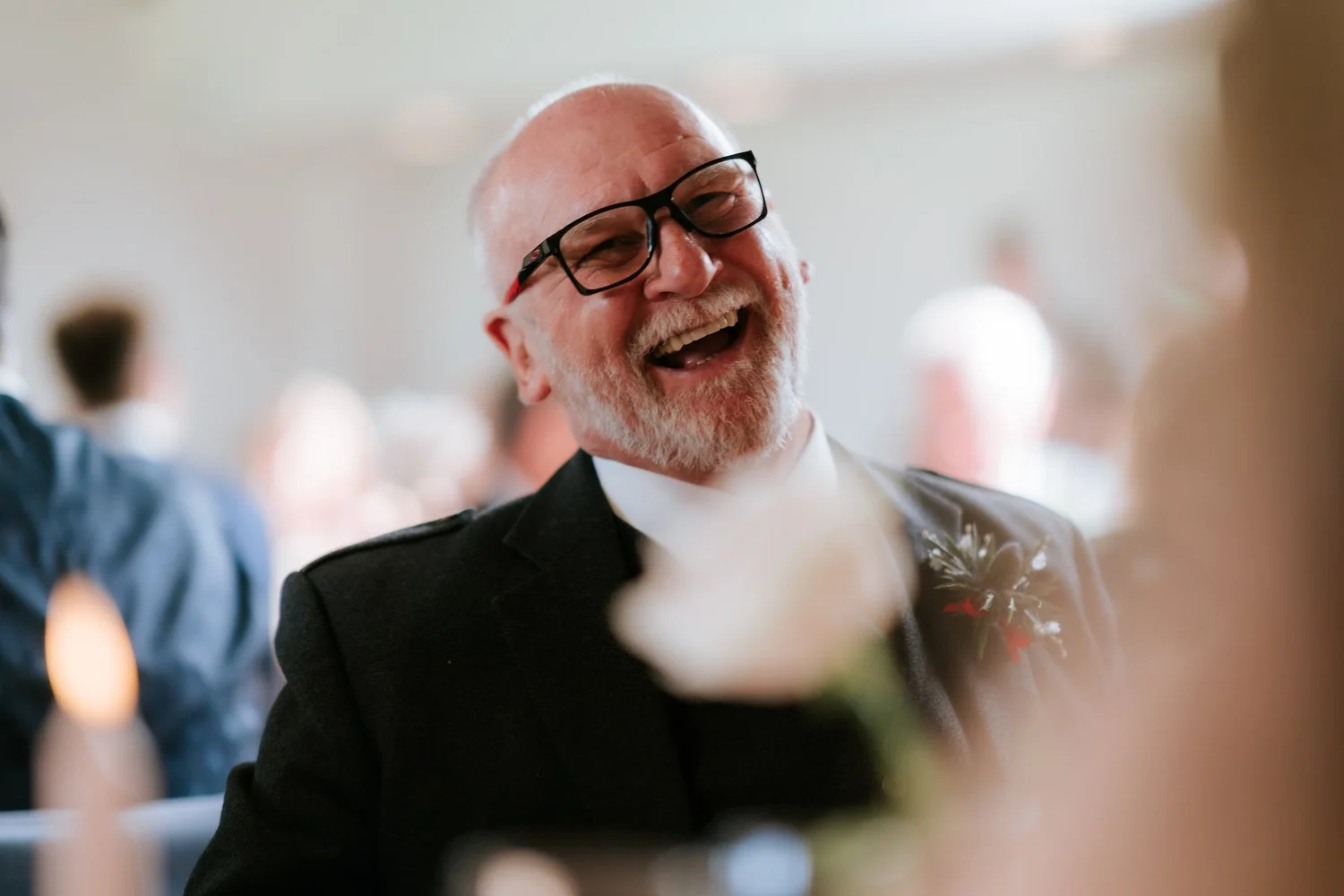 A guest laughing heartily at the wedding reception.