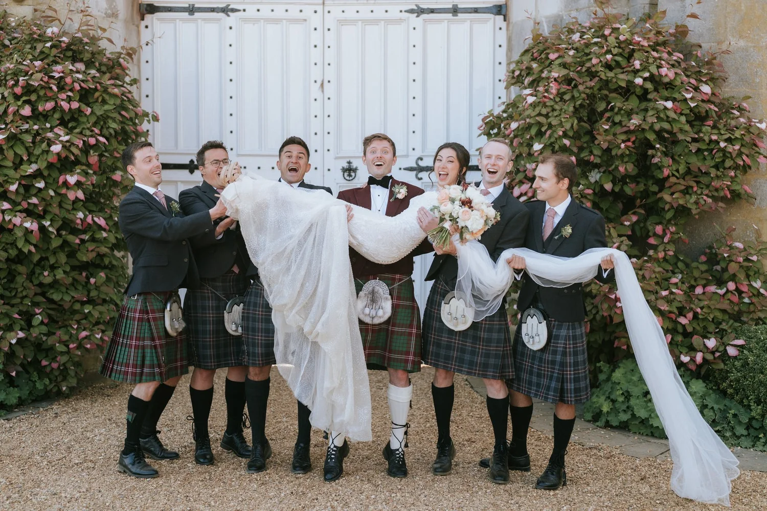 Kenneth and the groomsmen lifting Kim for a playful group photograph outside Dundas Castle.