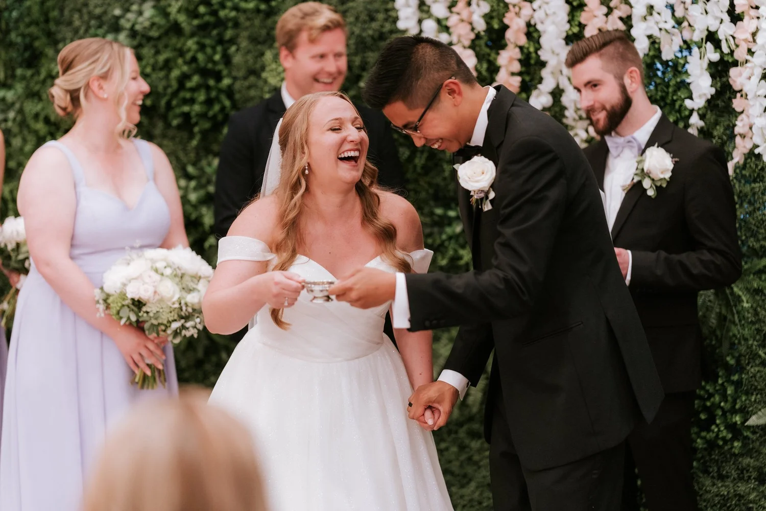 Allie laughing beside Carl and their wedding party in the Garden Suite.