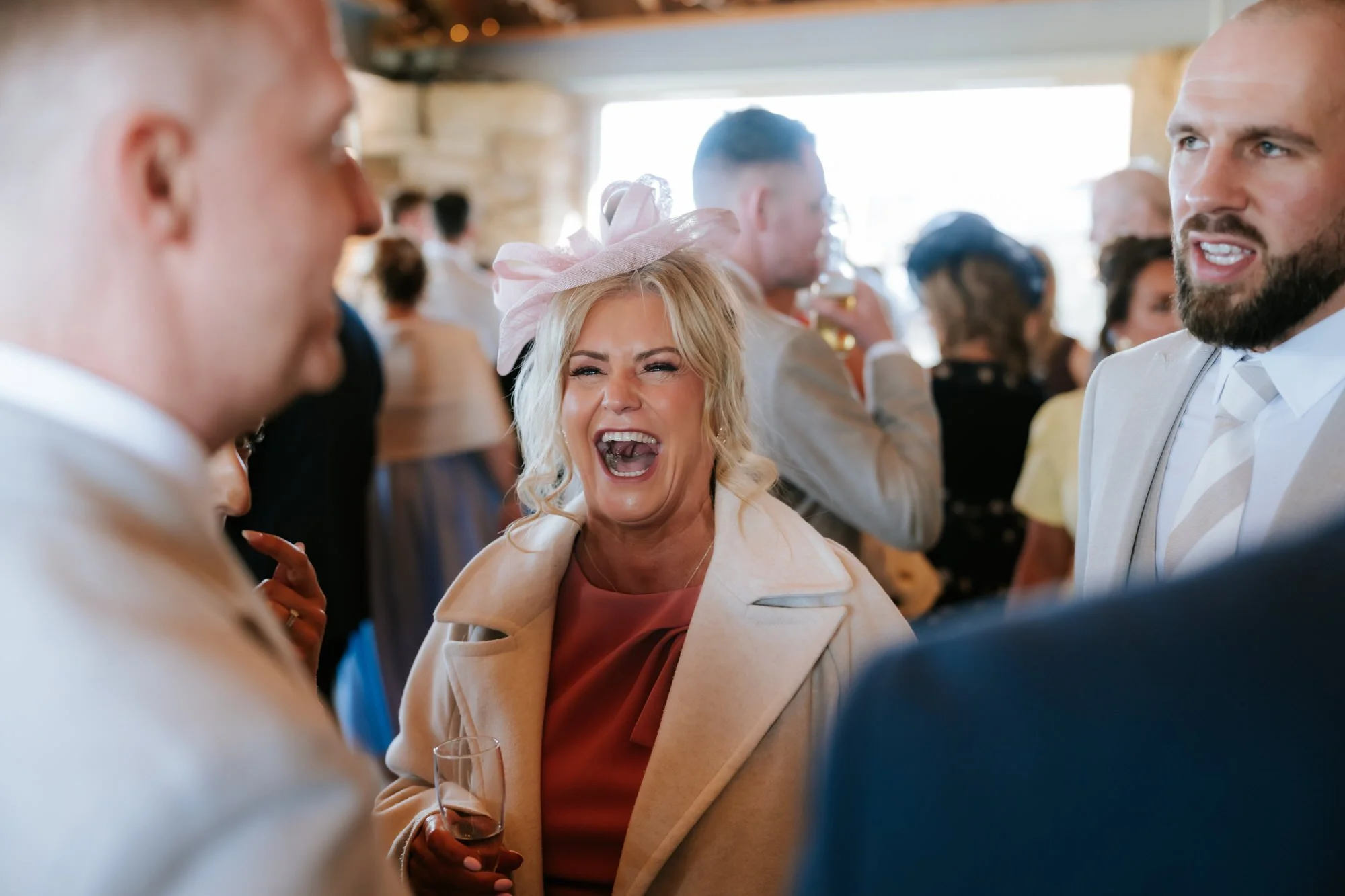 A wedding guest laughing among friends during the drinks reception