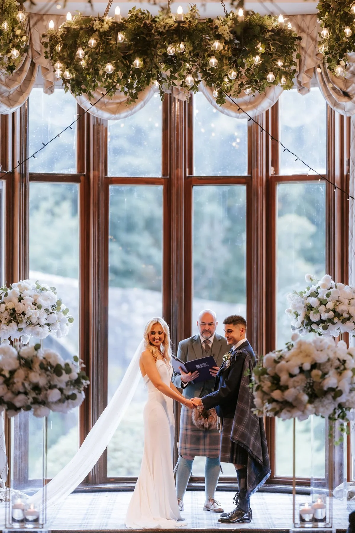 Lauren and Zen standing together on the ceremony stage in front of the tall windows.