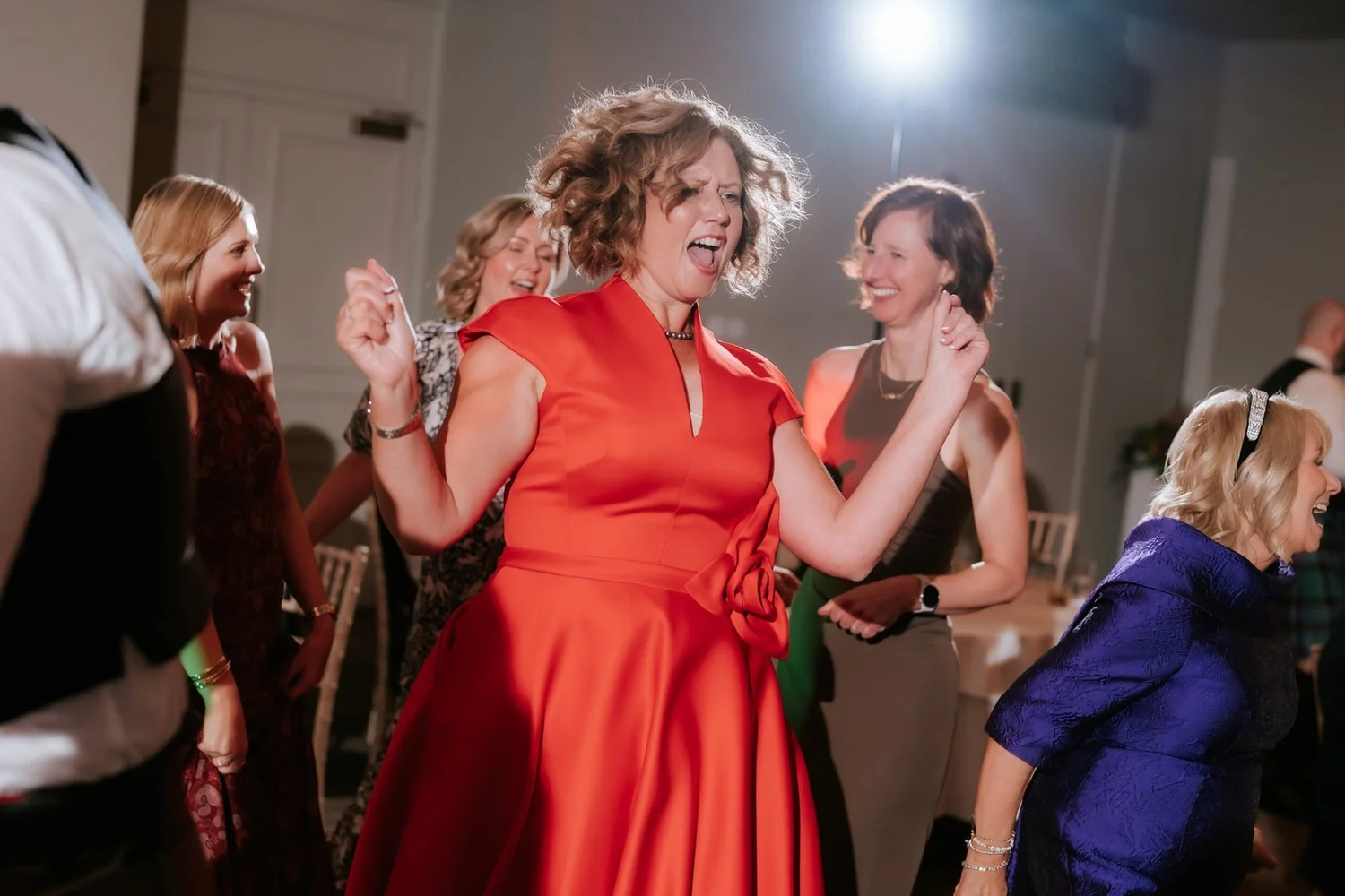 Two guests laughing and dancing together beneath the party lights.
