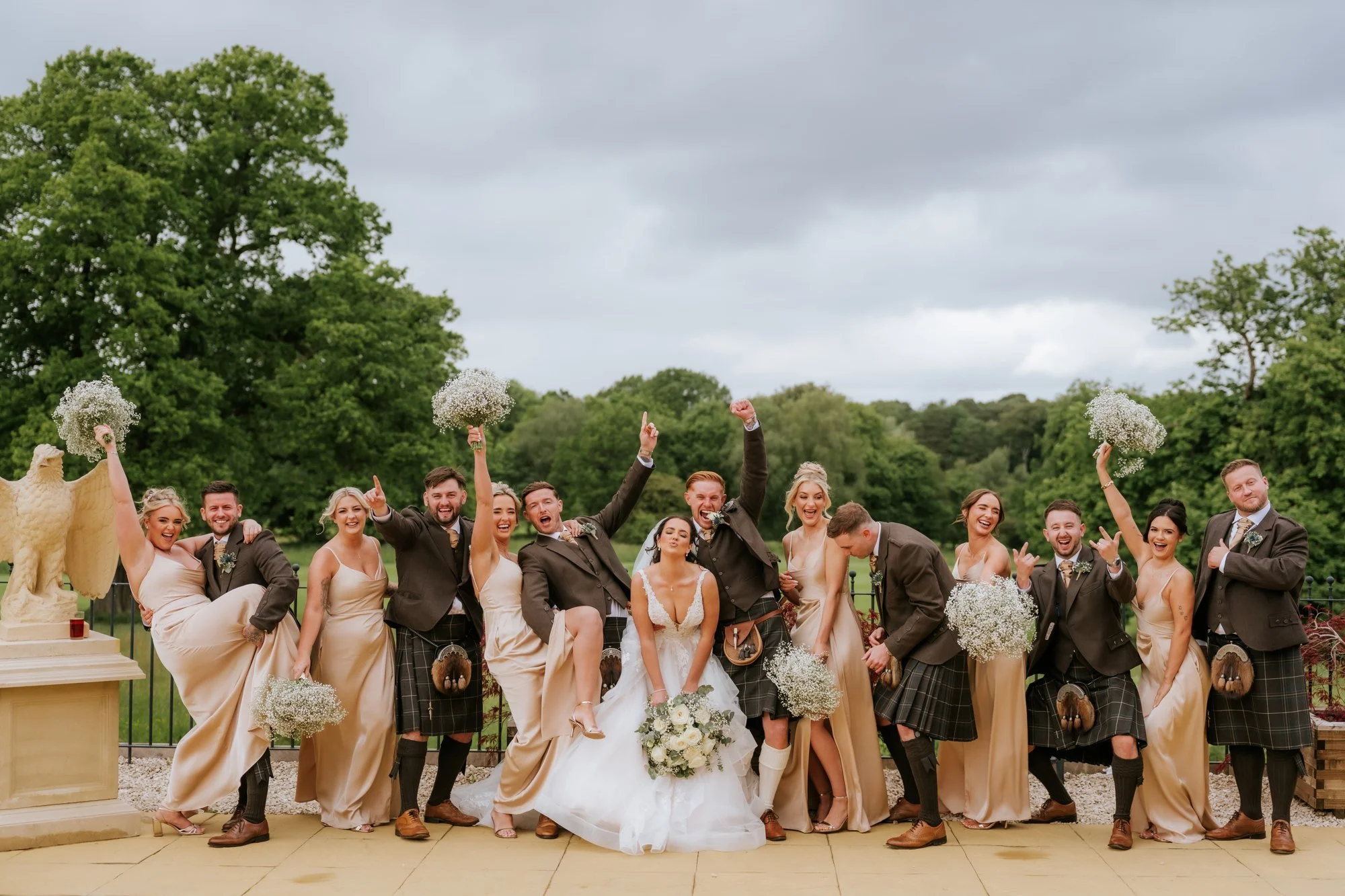 Bridesmaids raising bouquets beside the cheering groomsmen at Glenbervie House.