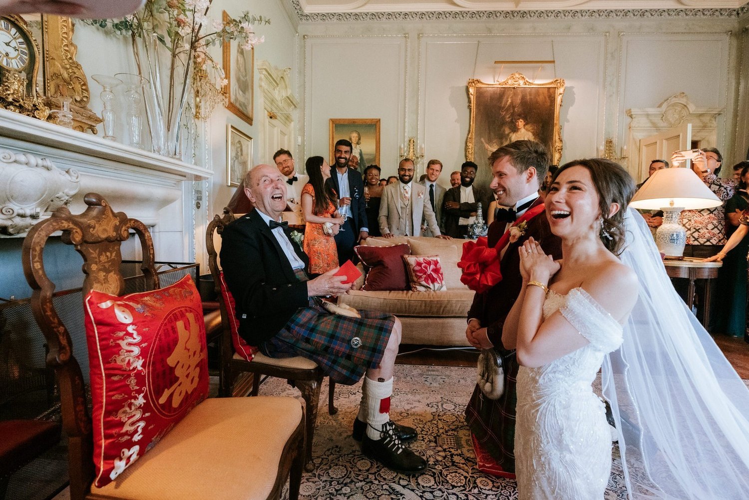 Kim and Kenneth laughing with family during their Chinese tea ceremony in an ornate room at Dundas Castle.