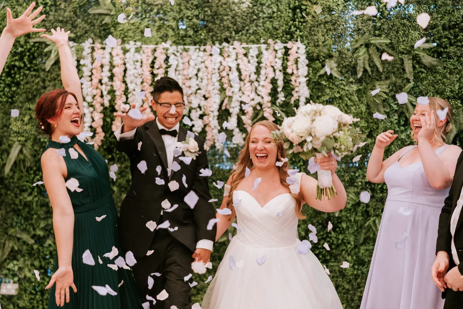 Allie and Carl laughing as their guests throw white confetti around them.