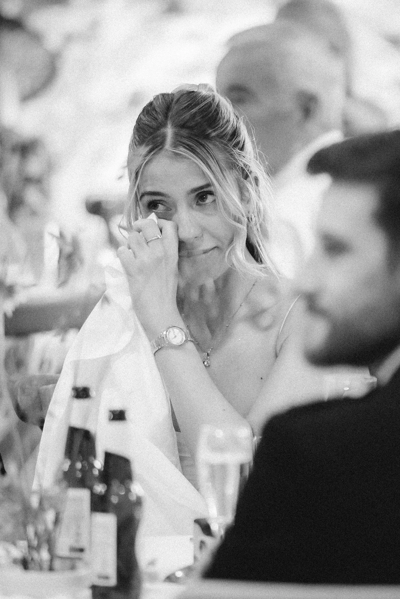 A guest wiping away a tear during the speeches, photographed in black and white.