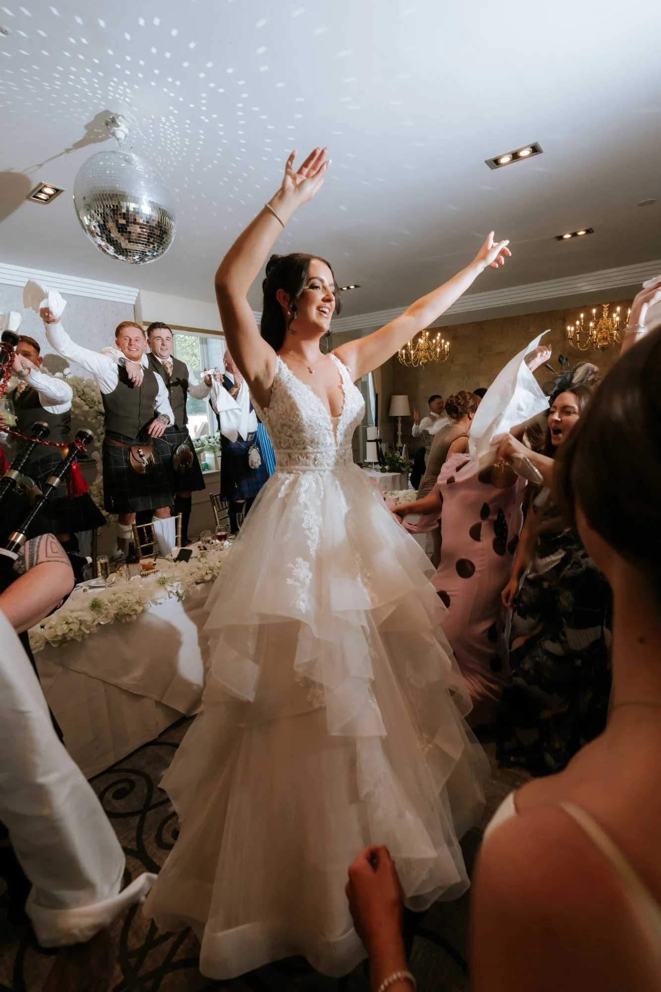Kaitlyn celebrating beneath a disco ball while guests wave napkins at Glenbervie House.