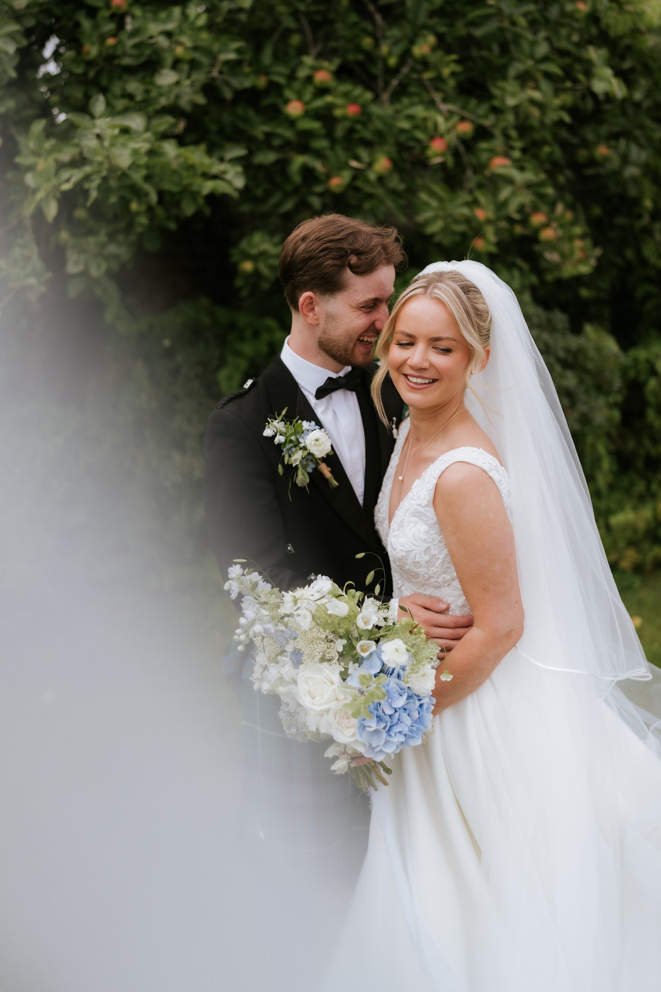 Lilian smiling with Luke beside her, framed by her veil.