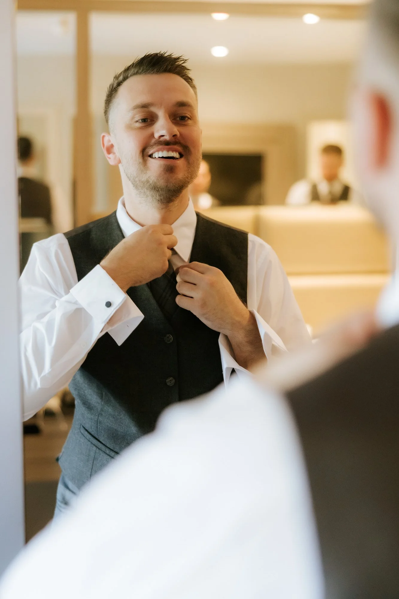 Adam adjusting his tie in the mirror before the wedding