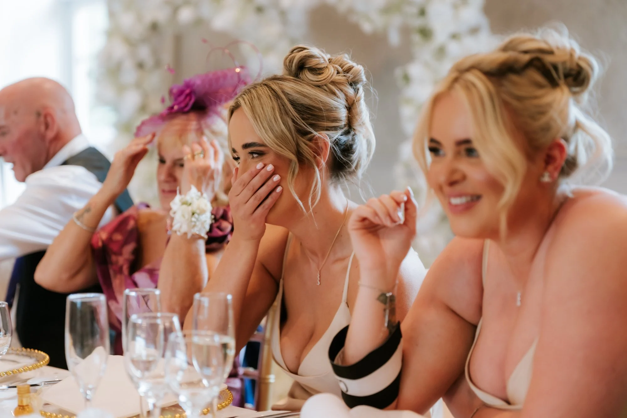 Bridesmaids laughing and covering their faces during the wedding speeches at Glenbervie House.
