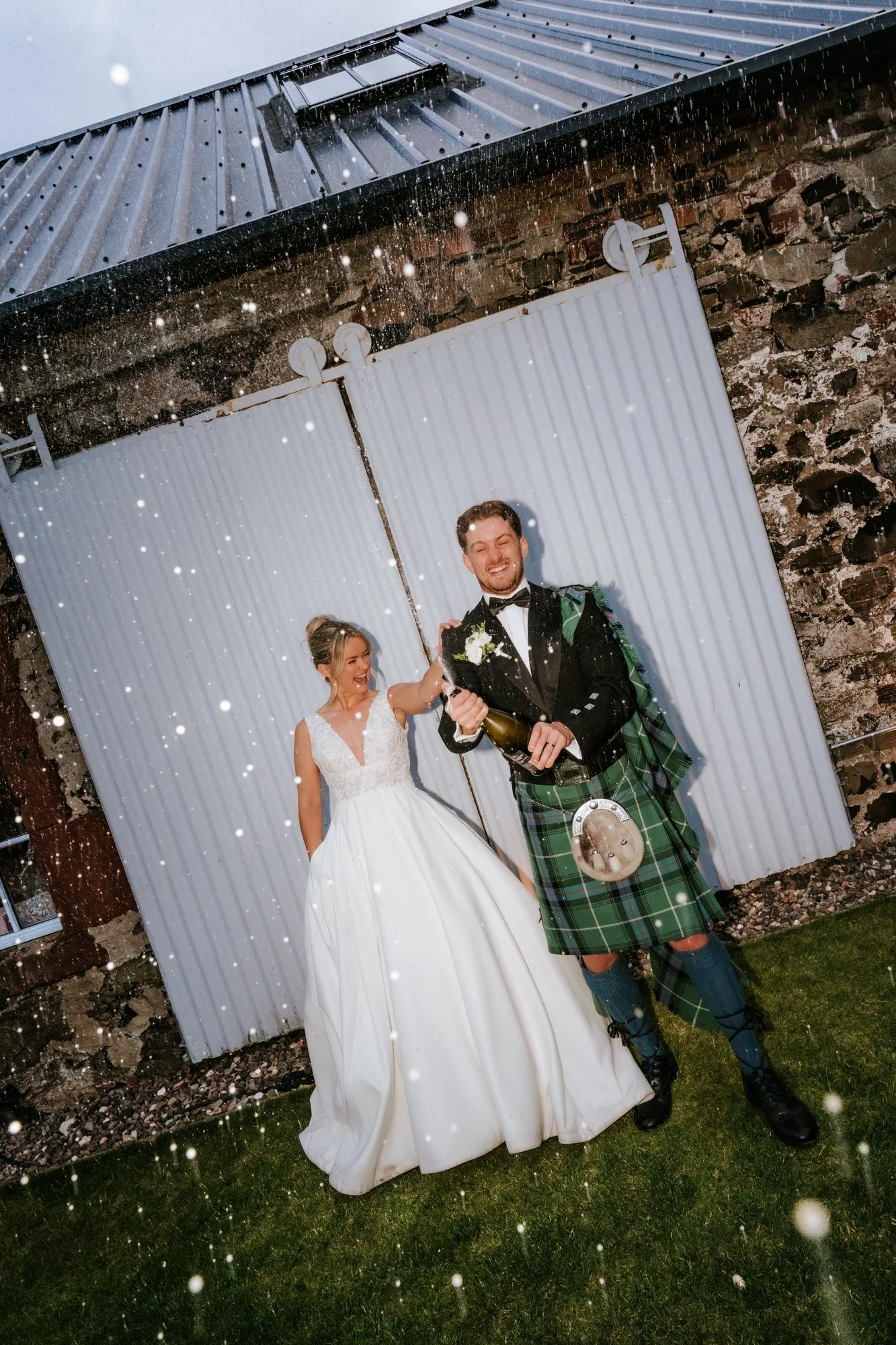 Lilian and Luke smiling outside the byre as bubbles float around them.