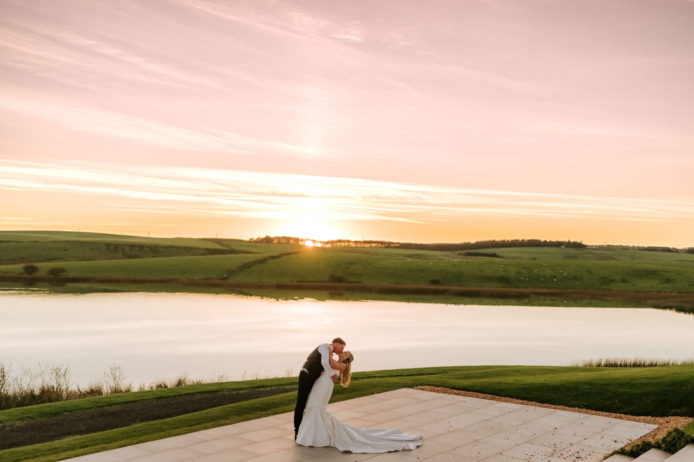Aiden dips Taylor for a kiss beside the loch at sunset at Lochside House Hotel.