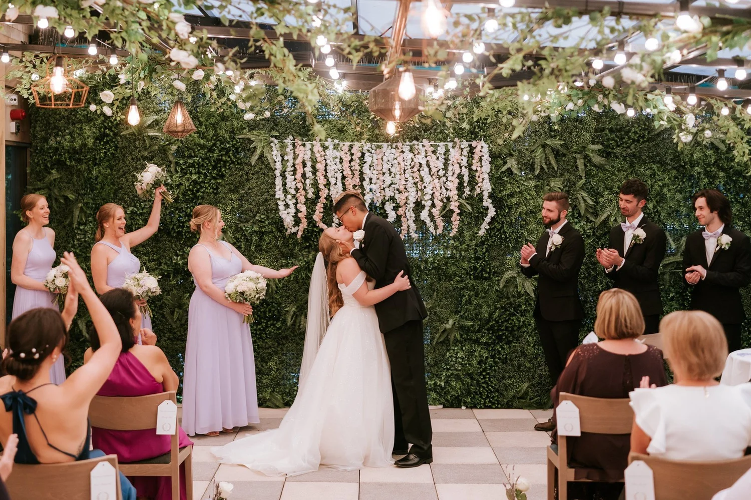 Allie and Carl kissing as their closest family and friends applaud in the Garden Suite.