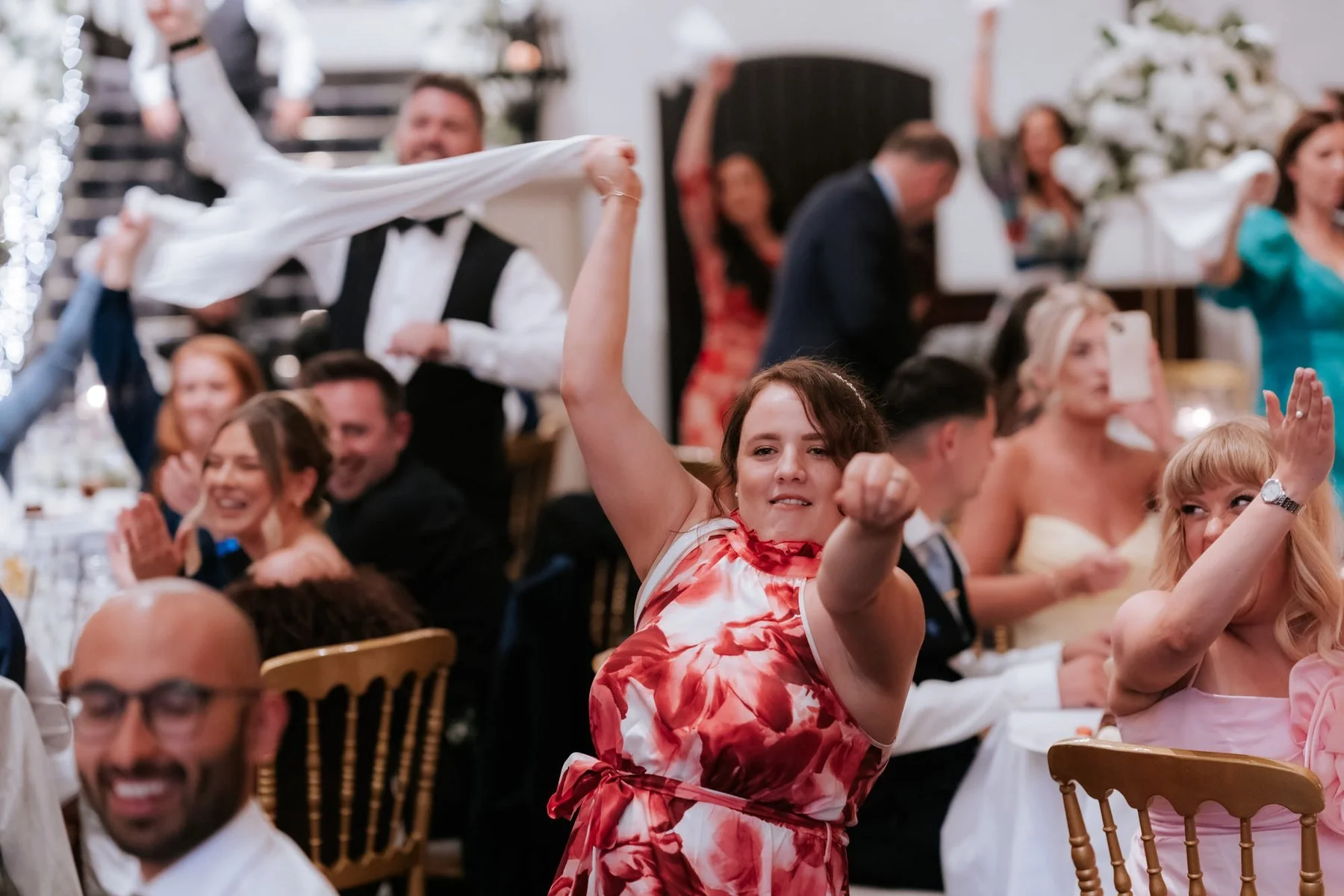 Guests waving napkins above their heads as the wedding party builds.