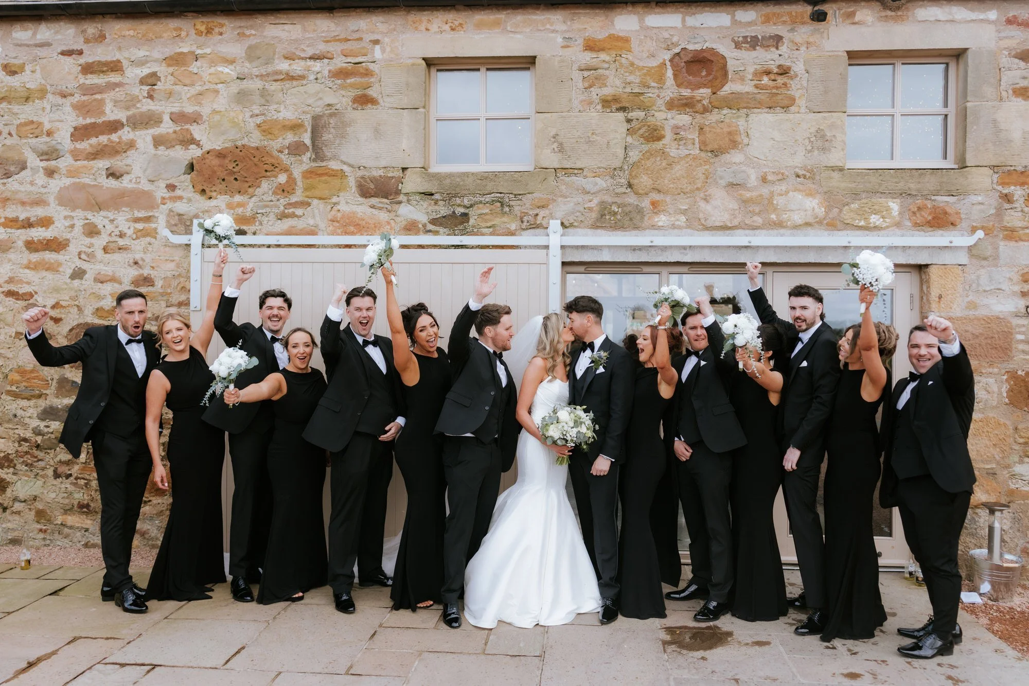 The wedding party cheering as Natalie and Jamie kiss