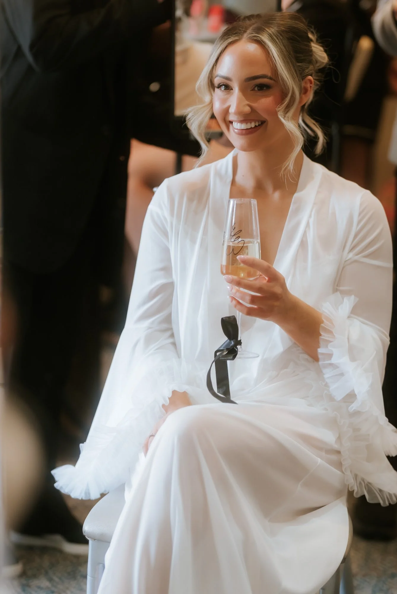 Elle smiling with a champagne flute during her bridal preparations