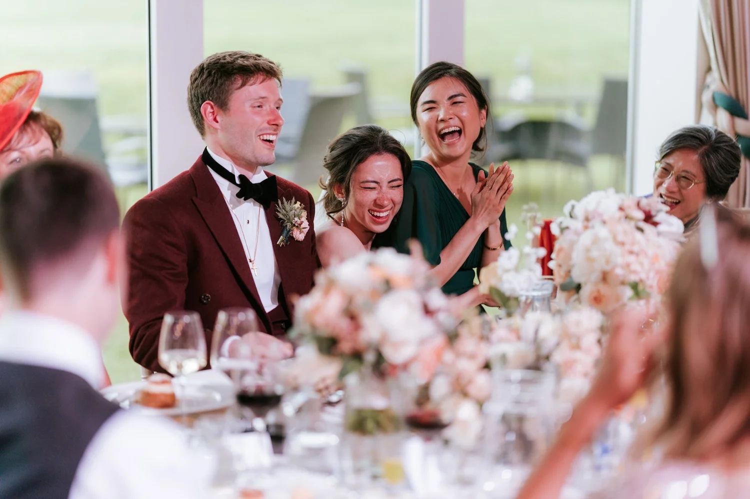 Kim, Kenneth and a bridesmaid laughing together at the wedding reception table.