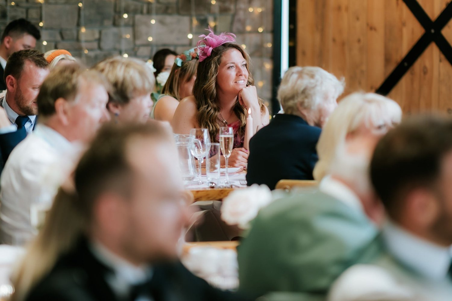 A guest covering her mouth as she reacts during the wedding reception.