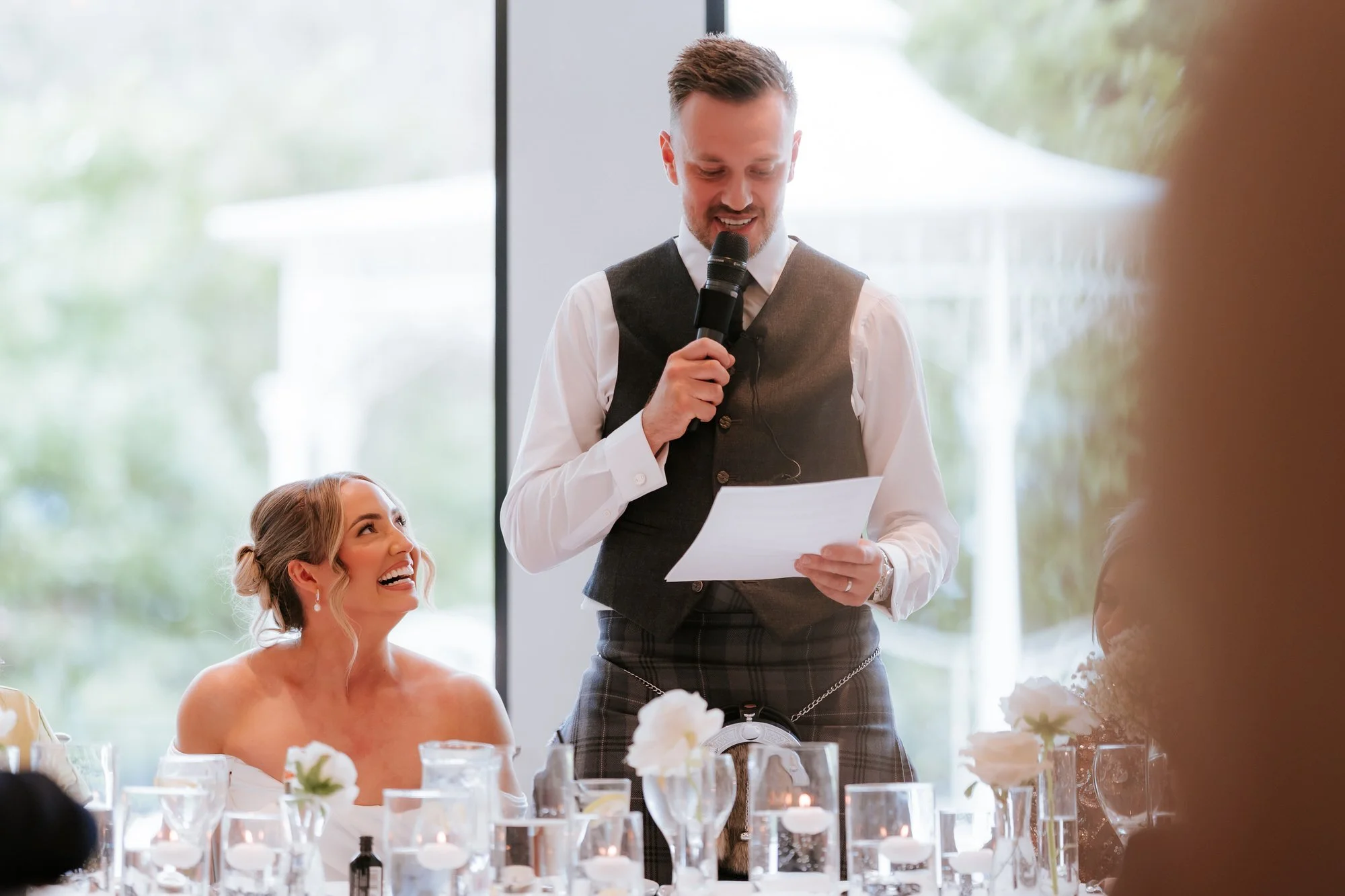 Elle looking up and laughing as Adam gives his wedding speech