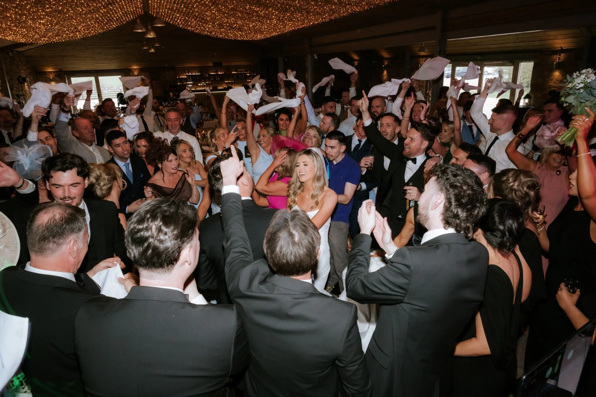Wedding guests waving napkins around the reception room