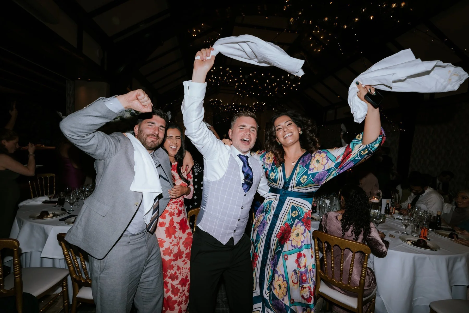 Wedding guests standing up and swinging napkins together.
