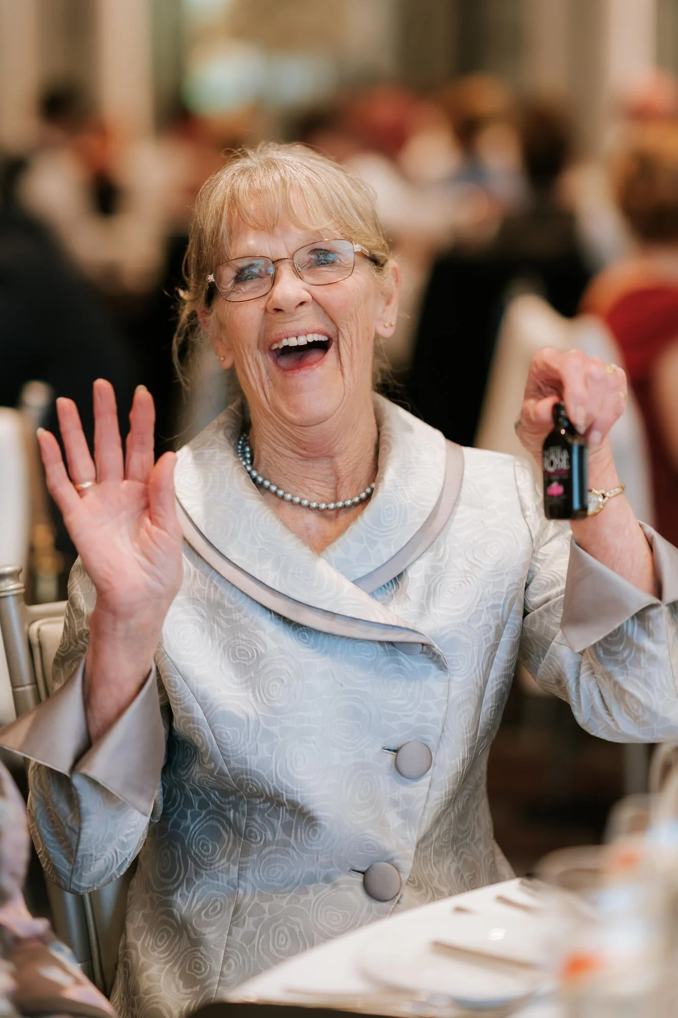 A wedding guest laughing while holding a miniature bottle